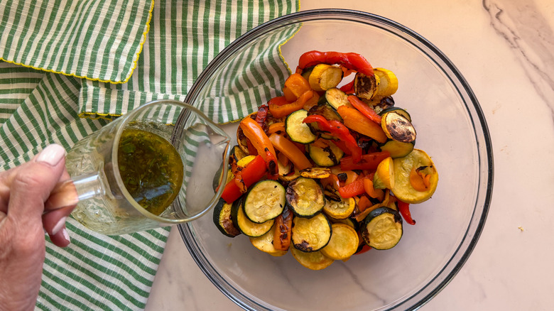 hand pouring marinade over grilled veggies