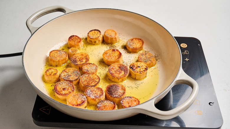 Pour the broth into the pan with the potatoes.