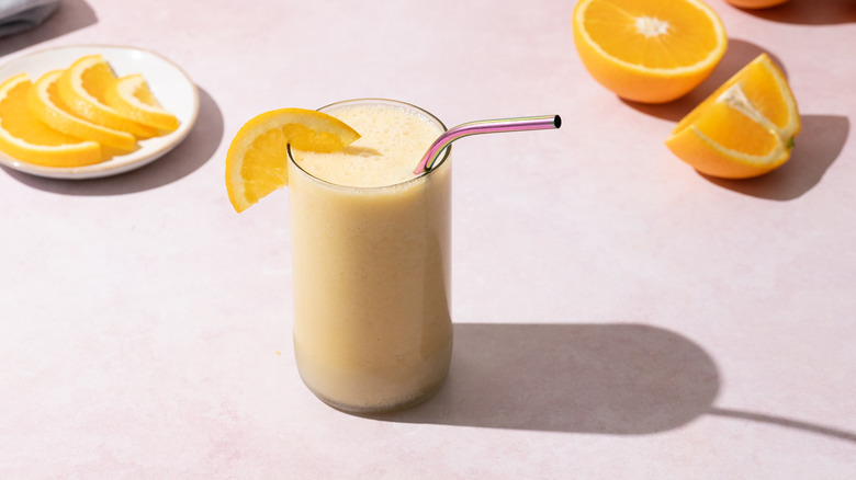 Orange cream smoothie with orange wedge and straw