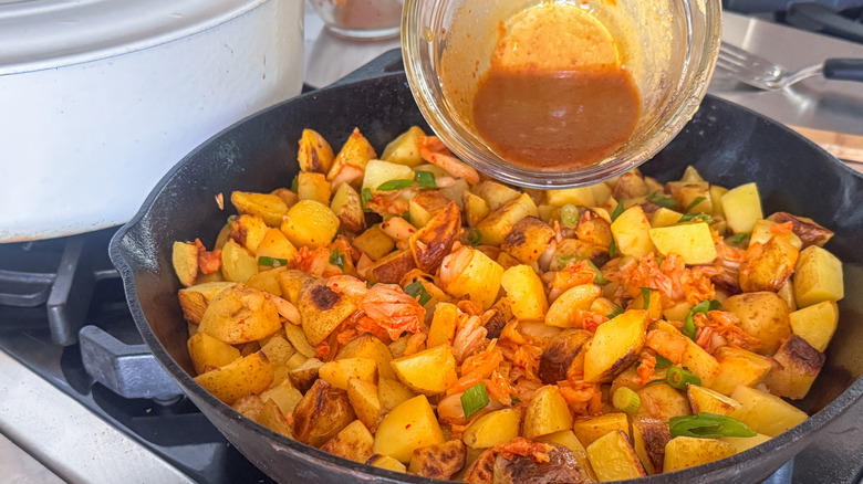 pouring sauce into pan with potatoes