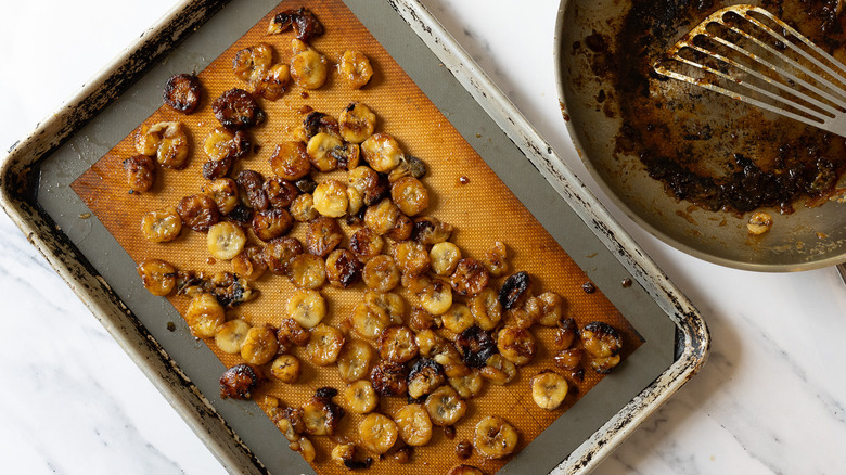 Flambeed bananas on baking sheet, and beside pan with bourbon drippings.