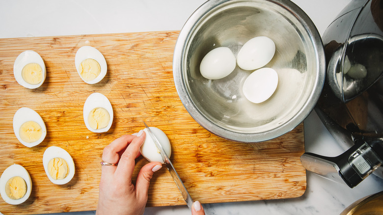 Cutting eggs on cutting board.