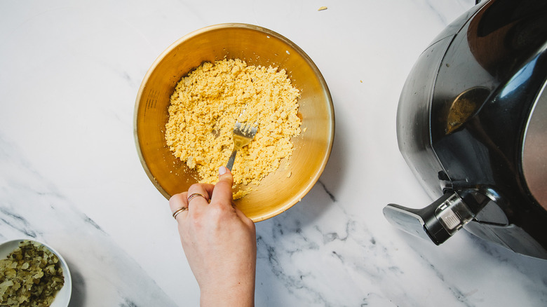 Mashing yolks with a fork in a bowl.