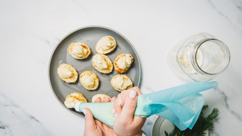 Filling egg whites with pickle devilled eggs filling.