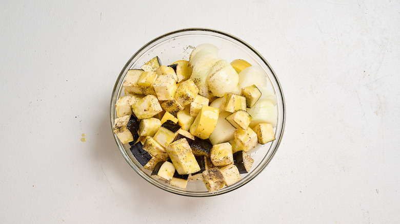 seasoning the vegetables with salt and pepper in a bowl