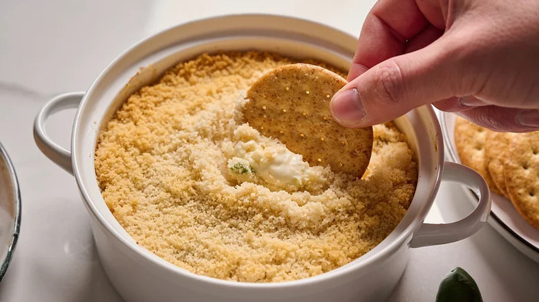 hand scooping dip with cracker