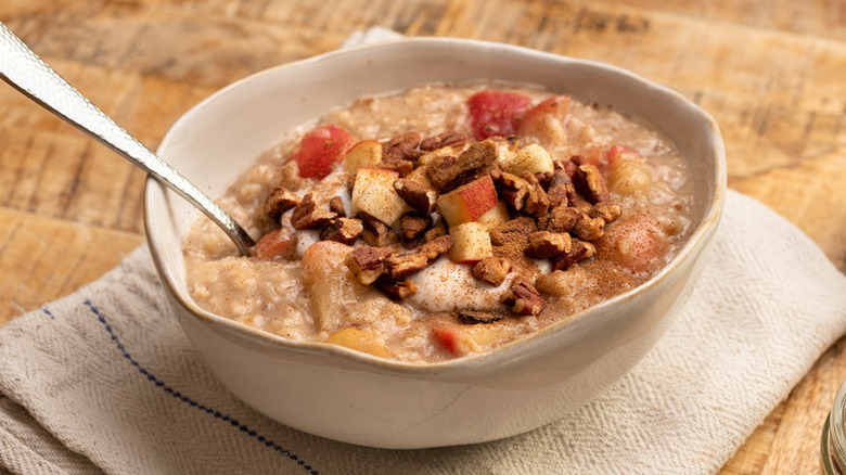 Apple cinnamon oatmeal in bowl, topped with chopped pecans