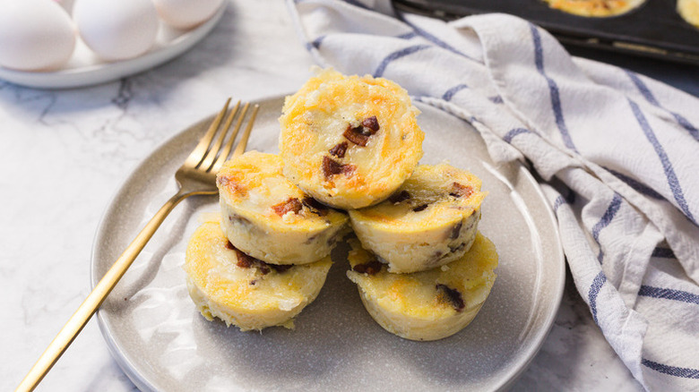 Pile of cheese and bacon egg bites on plate with fork