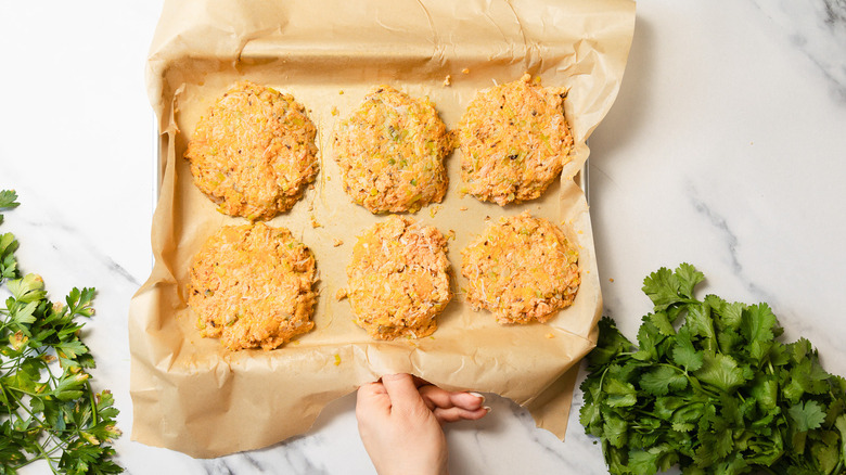 Six uncooked crab cakes on baking sheet
