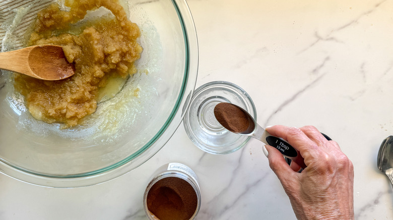 hand adding espresso to bowl next to bowl of butter and sugar mixture