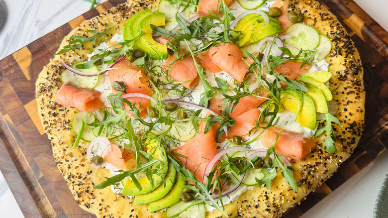 Bagels and lox inspired pizza on wooden board