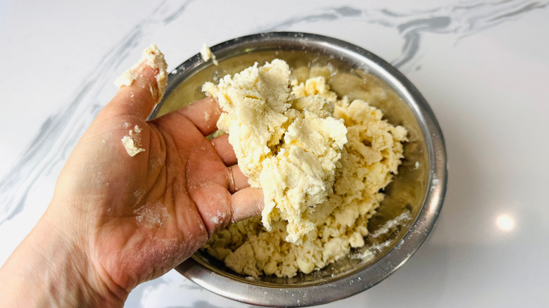 Hand holding dough over bowl