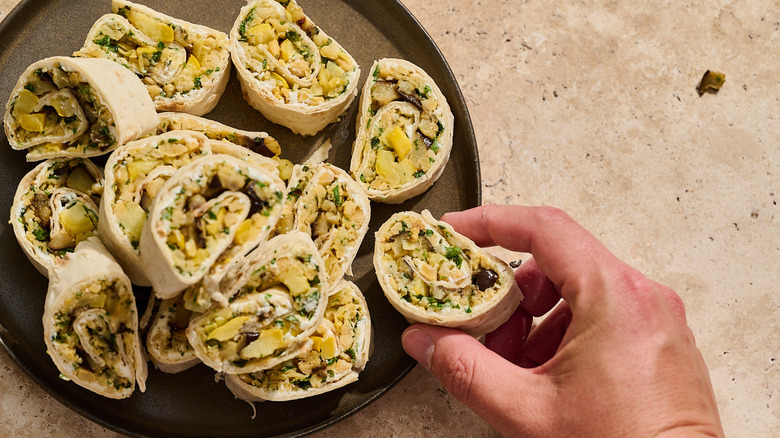 hand reaching to pick up a vegetable pinwheel