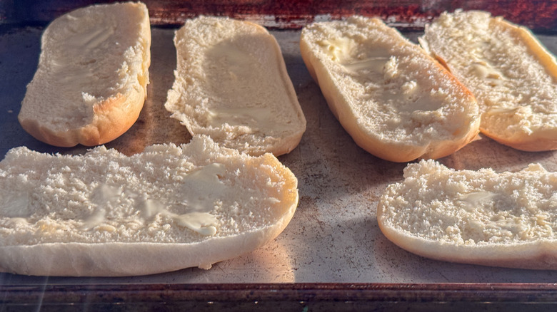 halved bread rolls on sheet pan in oven