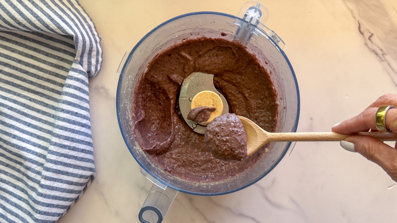 Spooning black bean puree out of food processor