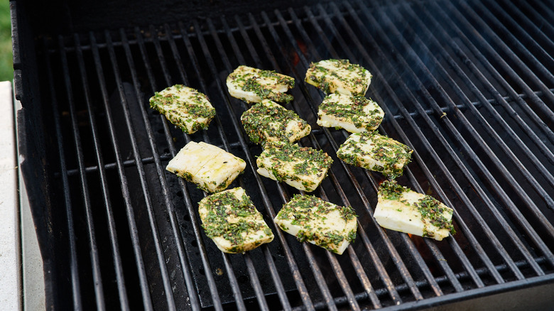 grilling marinated halloumi slices on a grill