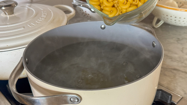 adding pasta to pot of water