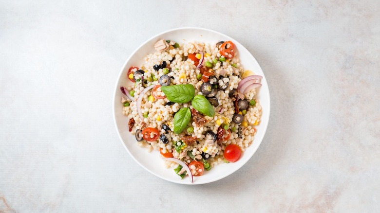 Tuna couscous salad garnished with basil on plate