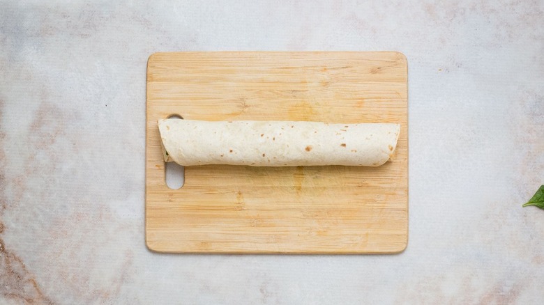 Rolled up tortilla on wooden board