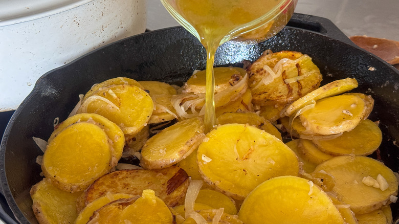 pouring broth into pan with potato slices