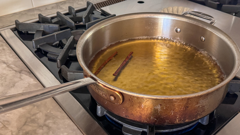 boiling cider and cinnamon sticks in pan