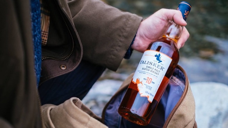 A person outdoors pulling a bottle of Talisker 10-year out of a bag
