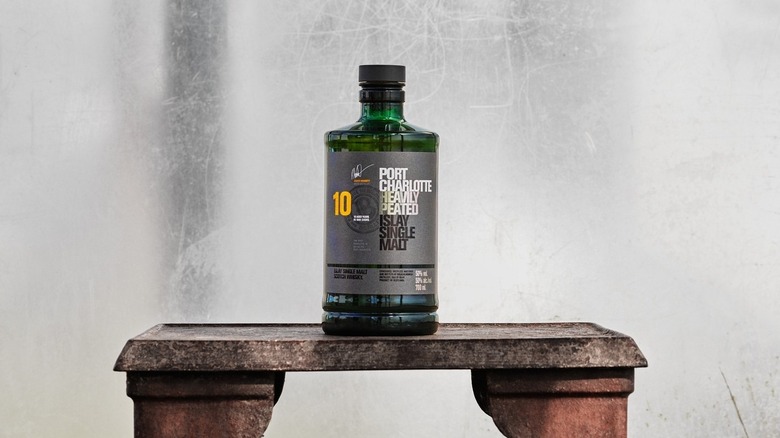 A bottle of Port Charlotte 10-year placed on a stone bench