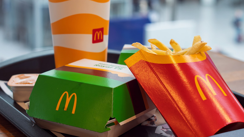 A meal from McDonald's featuring a sealed burger box next to some fries and a drink