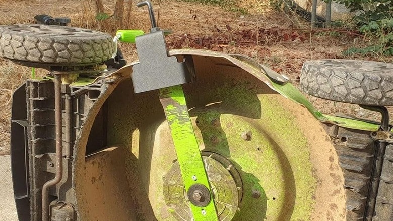 A black clamp holding a mower blade in place