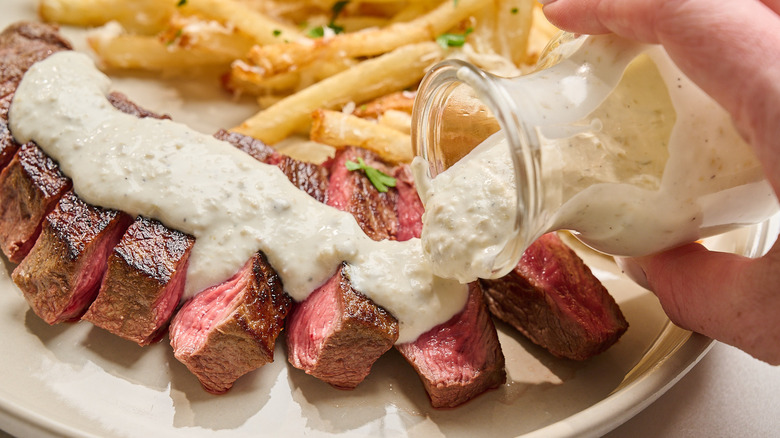 pouring blue cheese dressing over sliced steak
