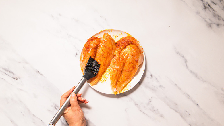 Brushing chicken with spices