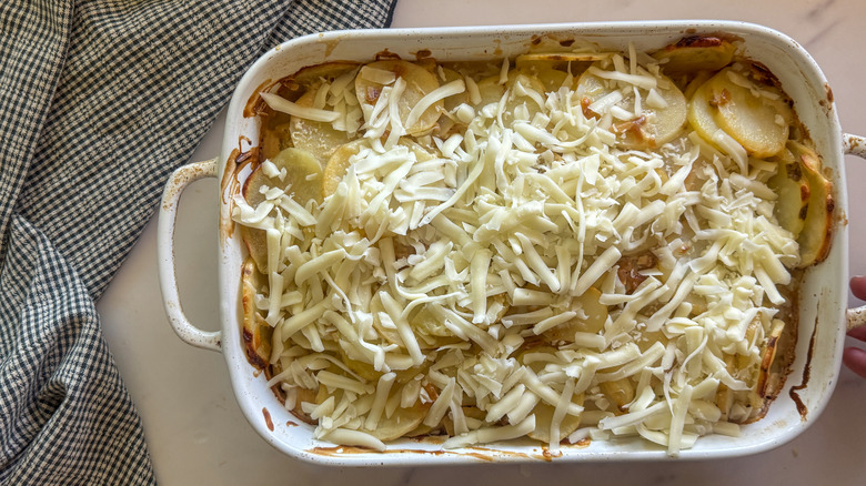 Potato casserole in baking dish topped with shredded cheese