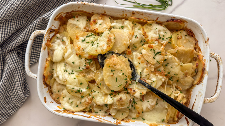 Cheesy french onion potato casserole in baking dish with serving spoon