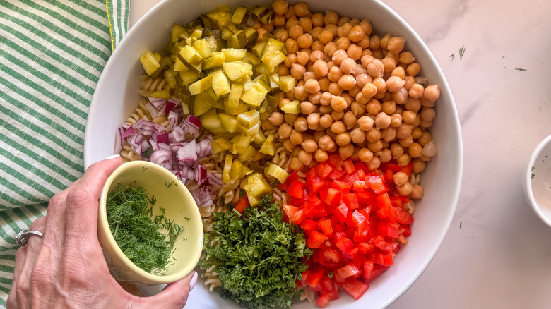 hand adding dill to bowl