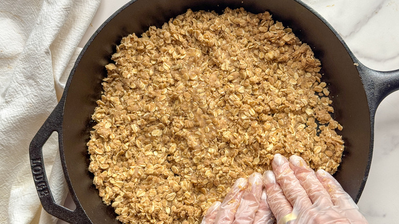 hands pressing crust into skillet