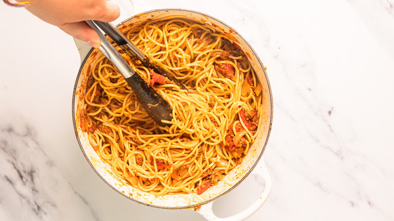 Stirring big pot of bourbon-infused cowboy spaghetti