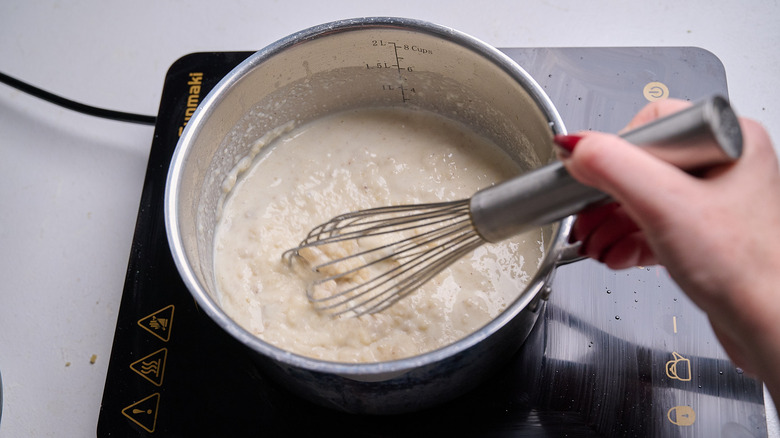 whisking milk into saucepan with roux