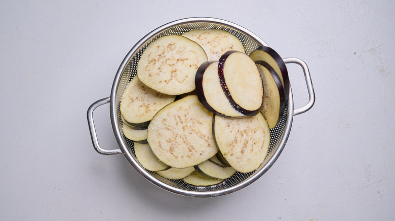 eggplant sprinkled with salt in a colander