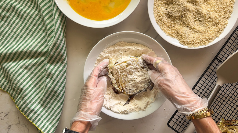 hands dredging steak in flour