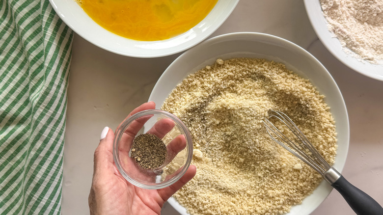 hand adding spices to panko
