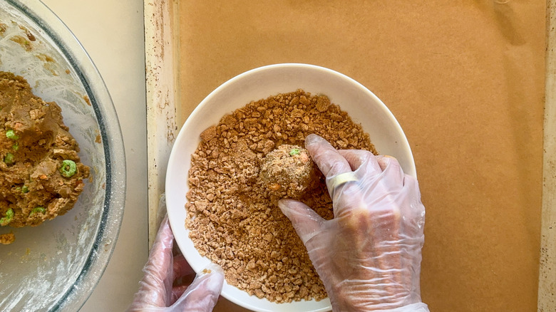 hands rolling dough in crumbs