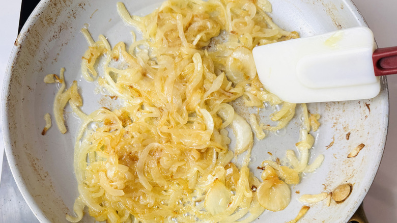 Sauteed onions and rubber spatula in pan
