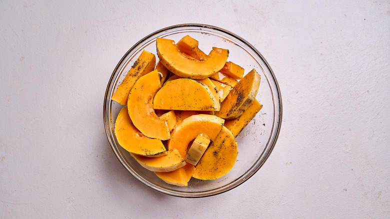 squash tossed with oil and seasoning in a bowl