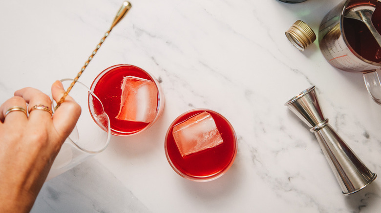 Pouring negroni into glasses over ice