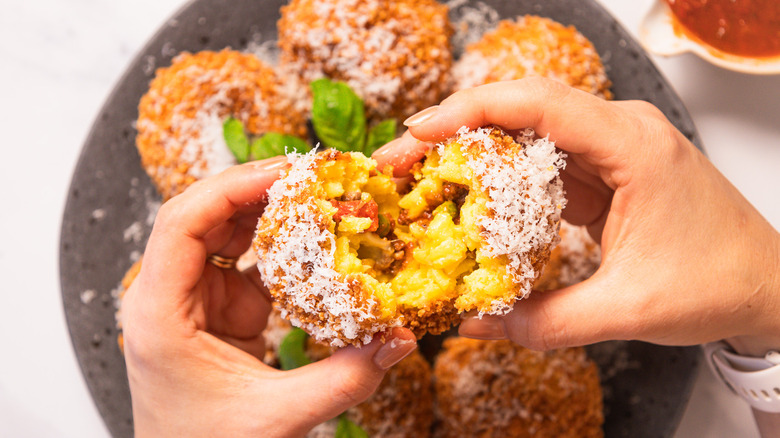 Ripping an arancini in half over a plate
