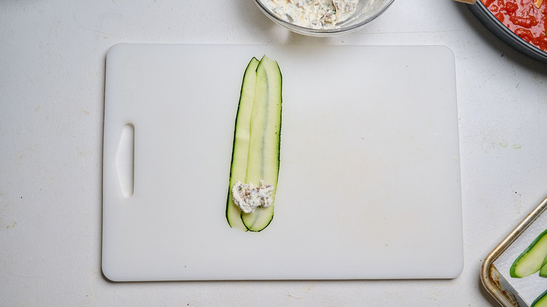 zucchini ribbons on a cutting board with a scoop of filling