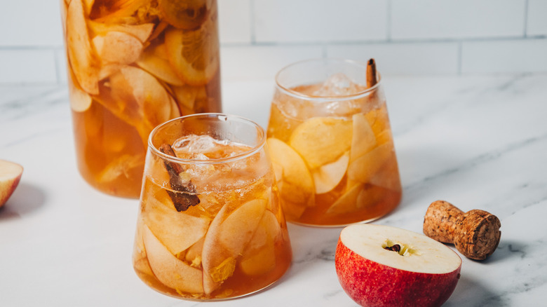 Pitcher and two glasses of of apple sangria beside apple