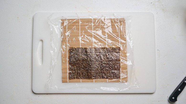 nori sheet on mat over plastic wrap