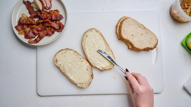 spreading butter onto bread on a plate