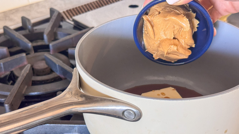 hand adding peanut butter to pot